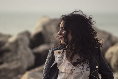 Woman with curly hair standing against sky