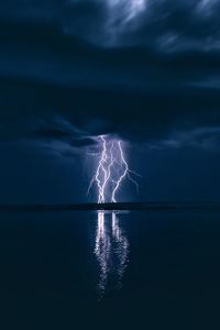 Lightning over sea against storm clouds