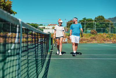 Full length of woman standing on chainlink fence