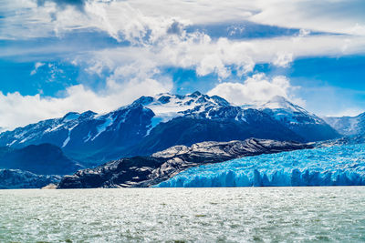 Scenic view of glacier and snowcapped mountains against sky