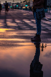 Low section of woman walking on road at sunset