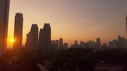 Modern buildings in city against sky during sunset