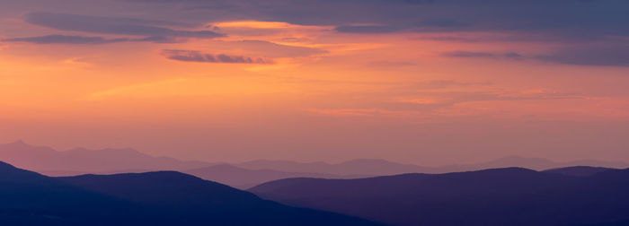 Scenic view of silhouette mountains against romantic sky at sunset