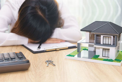 Woman sleeping on document with model home on table