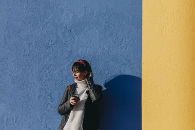 Full length of woman standing against wall