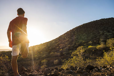 Rear view of man standing on mountain against sky