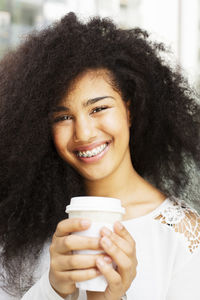 Portrait of smiling teenage girl with disposable cup