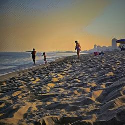 People on beach against sky during sunset
