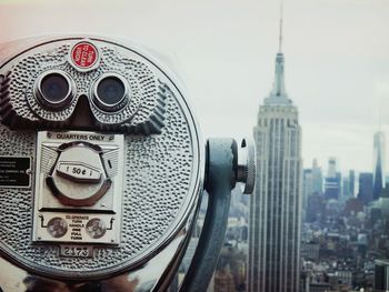 Close-up of coin-operated binoculars at observation point against cityscape