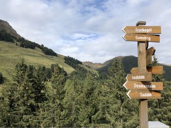 Information sign by tree against sky