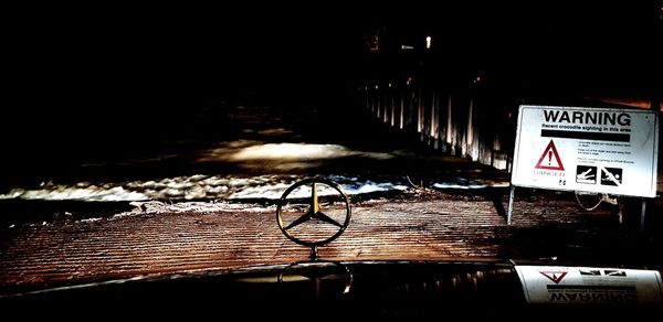 Illuminated sign by river against sky at night