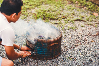 Cropped image of man burning fire in fire pit