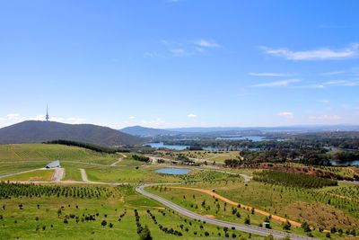 High angle view of grassy field and river against blue sky