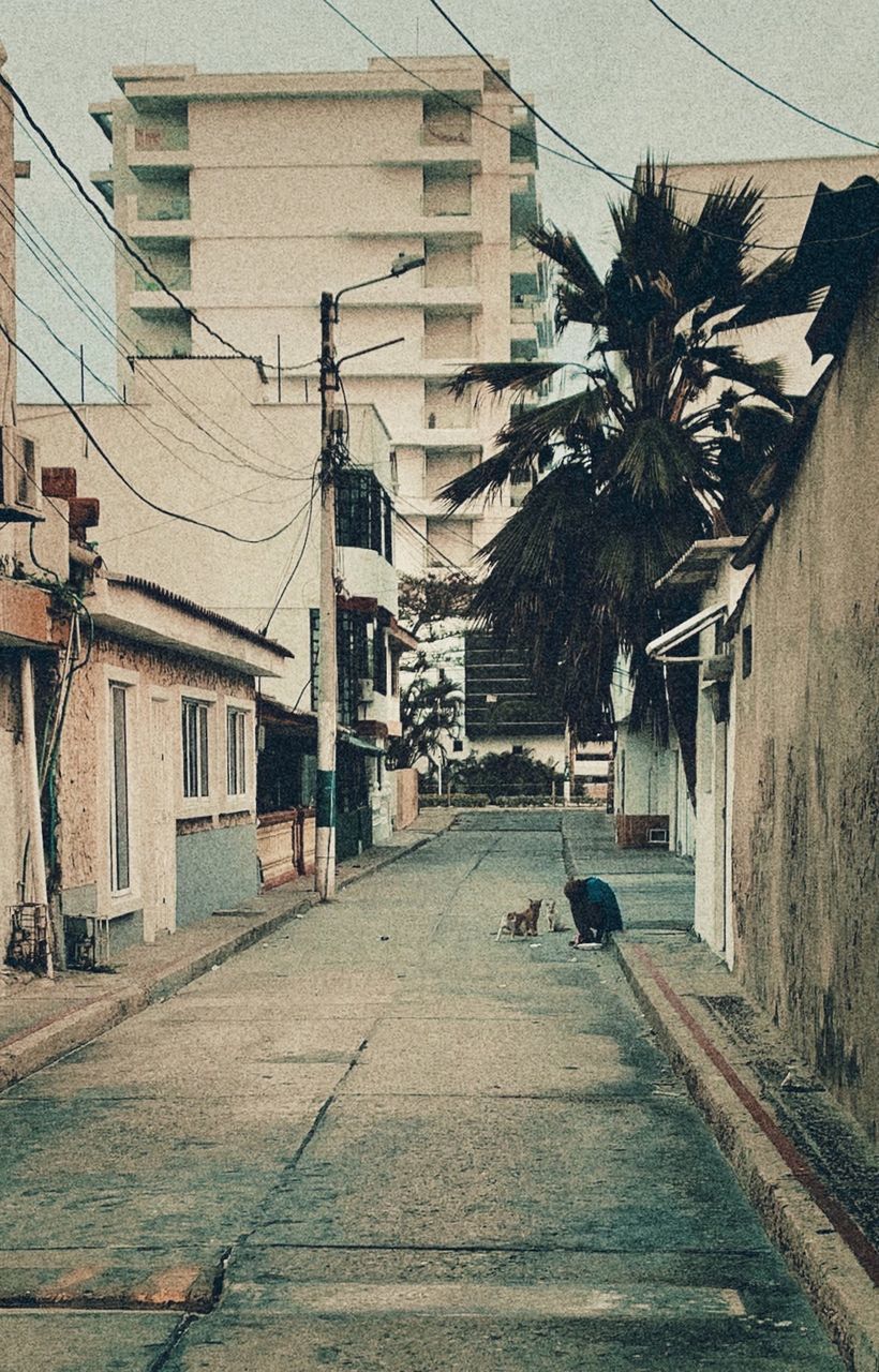 PEOPLE WALKING ON STREET AMIDST BUILDINGS