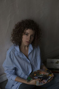 Portrait of young woman sitting against wall