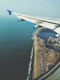 Aerial view of airplane flying over sea against sky