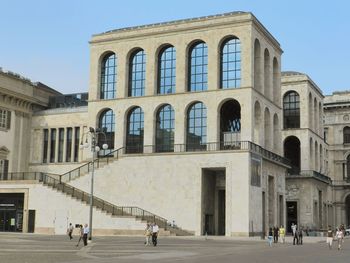 People in front of building against clear sky