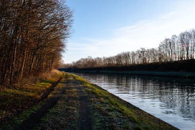 Scenic view of road by lake against sky
