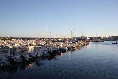 Sailboats moored in sea against clear blue sky