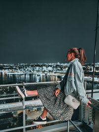 Side view of woman sitting on railroad track