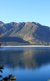 Scenic view of lake and mountains against clear blue sky