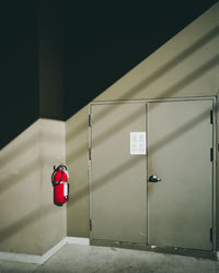 Wall mounted red fire extinguisher in front of the door of control room.