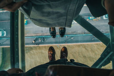 Low section of men standing on transparent floor