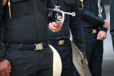 Midsection of man holding camera while standing against people