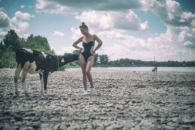 Woman standing by cow at lakeshore