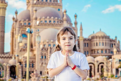 Portrait of young woman standing against buildings in city