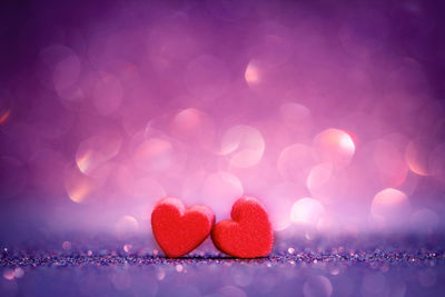 Close-up of heart shape decorations on table against purple background