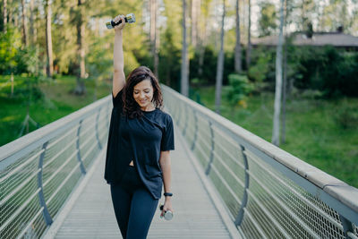 Portrait of woman standing on footbridge