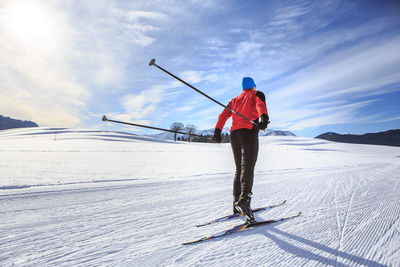 Rear view of person skiing on snowcapped mountain against sky