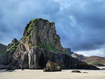 Rock formation on beach against sky