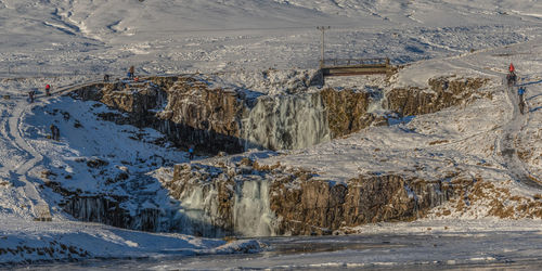 Panoramic view of tourists and photographers at a frozen waterfall