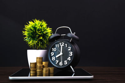 Close-up of clock on table against black background