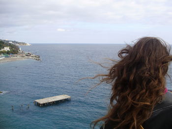 Rear view of woman by sea against sky