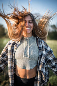 Smiling woman with tousled hair standing outdoors