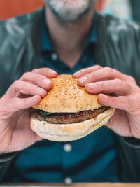 Midsection of man holding burger