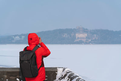 Rear view of man standing on snow against sky