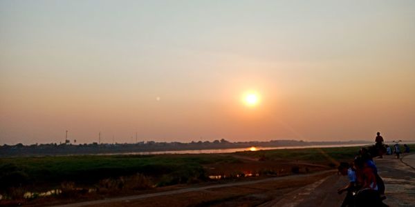 Rear view of woman riding on landscape against sky during sunset