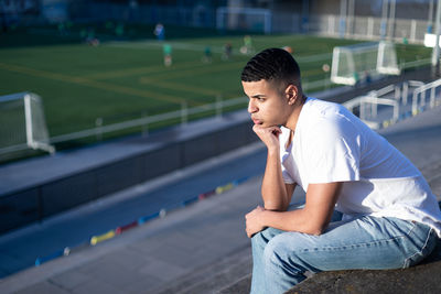 Young man looking away while sitting on staircase