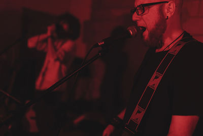 Group of musicians playing in red neon lights at music studio