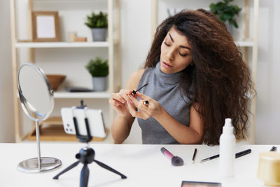 Woman doing make-up while blogging through smart phone