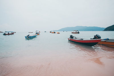 Boats moored on sea against clear sky