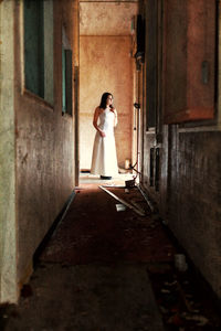 Side view of woman standing at entrance of building