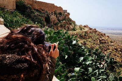 Rear view of man photographing by sea against sky