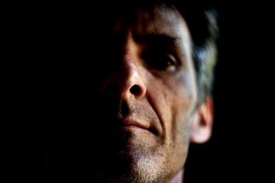 Close-up portrait of young man over black background