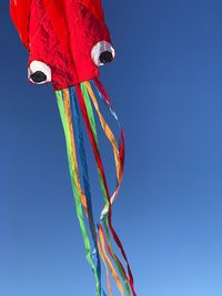 Low angle view of red flag against clear blue sky