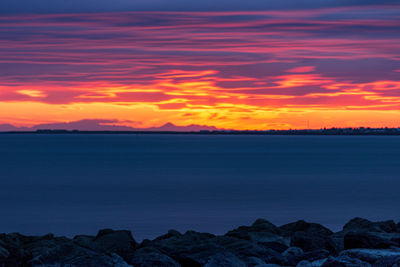 Scenic view of sea against dramatic sky during sunset